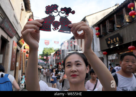 Un turista visualizza una carta-taglio effettuato dal folk cinese artista Xie Jianqing per la prossima festa Qixi o 'Double sette Festival", noto anche come il C Foto Stock