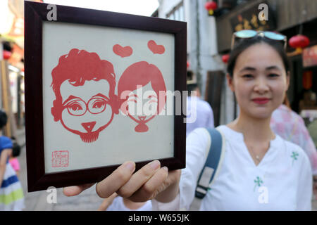 Un turista visualizza una carta-taglio effettuato dal folk cinese artista Xie Jianqing per la prossima festa Qixi o 'Double sette Festival", noto anche come il C Foto Stock