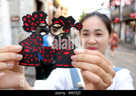 Un turista visualizza una carta-taglio effettuato dal folk cinese artista Xie Jianqing per la prossima festa Qixi o 'Double sette Festival", noto anche come il C Foto Stock