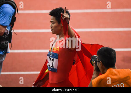 Su Bingtian della Cina pone con la bandiera nazionale cinese per festeggiare dopo la conquista degli uomini 100m finale delle gare di atletica durante il 2018 Asi Foto Stock