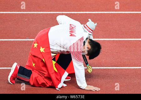 Su Bingtian della Cina pone con la bandiera nazionale cinese per festeggiare dopo la conquista degli uomini 100m finale delle gare di atletica durante il 2018 Asi Foto Stock