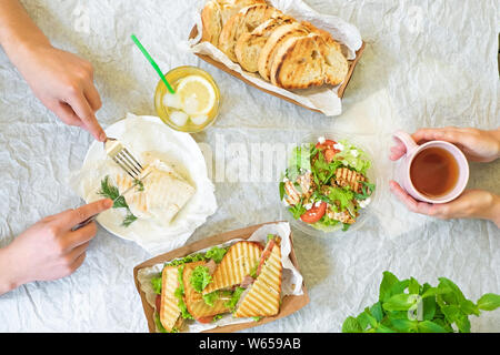 La caesar salad, bruschette, prosciutto e pomodoro panini tabella con le mani, vista in pianta da sopra Foto Stock