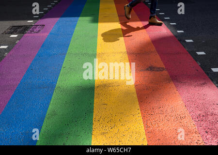 London, Regno Unito - 11 Luglio 2019: Un uomo cammina su Orgoglio LGBT rainbow dipinta su strada invece di regolari street attraversamento pedonale con un suggestivo te Foto Stock