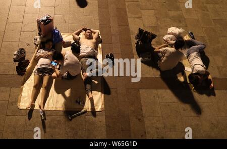 Passeggeri cinesi dormire e attendere per i loro treni presso la piazza della Stazione Ferroviaria di Pechino in Cina, 18 agosto 2018. Passeggeri cinesi sl Foto Stock