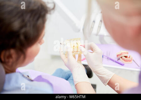 Assistente dentale mostra su un modello della dentatura destra spazzolatura con lo spazzolino interdentale Foto Stock