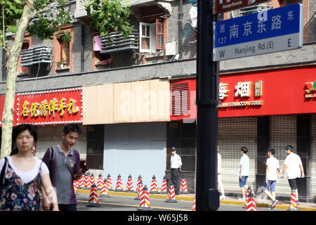 I pedoni a piedi passato il negozio di souvenir dopo la sua cartello collassato, uccidendo 3 persone e il ferimento di altre 6 persone, su East Nanjing Road in Huangpu District Foto Stock