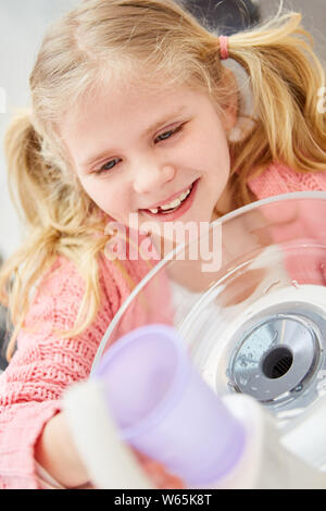 Bambina presso il dentista sciacqua la bocca con un bicchiere d'acqua per l'igiene orale Foto Stock