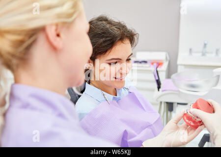 Assistente dentale mostra paziente su un modello di protesi per effetto del previsto le bretelle Foto Stock