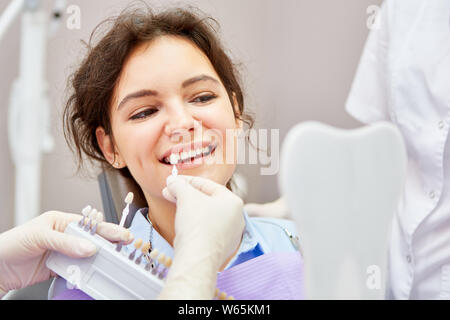 Sorridente giovane donna in cosmetica professionale per lo sbiancamento dei denti dal dentista Foto Stock