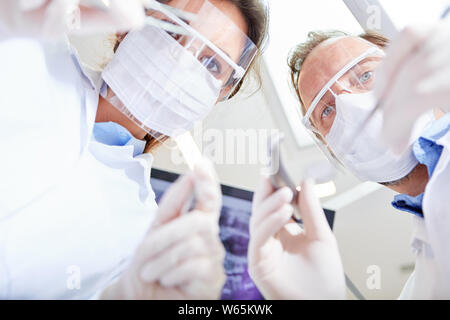 Due medici come chirurghi in un funzionamento di emergenza in chirurgia orale di una clinica dentale Foto Stock