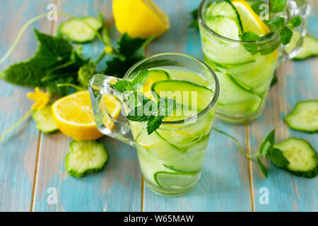 Occhiali con fresche biologiche freddo e rinfrescante infuso detox Acqua con limone e cetriolo su un tavolo di legno. Foto Stock