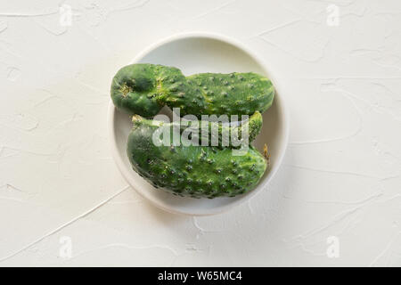 Brutto anormale organico due cetriolo su cemento bianco tavola. Concetto verdure organiche. Close up. Foto Stock