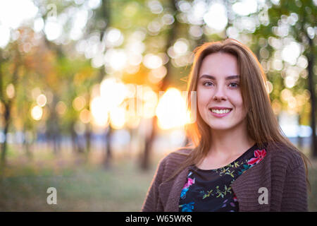 Felice bruna ragazza in posa di autunno park su alberi giallo dello sfondo. Foto Stock