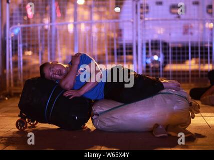 Un passeggero cinese dorme e attende il suo treno presso la piazza della Stazione Ferroviaria di Pechino in Cina, 18 agosto 2018. Passeggeri cinesi sl Foto Stock