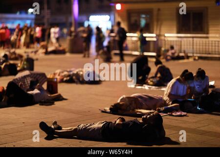 Passeggeri cinesi dormire e attendere per i loro treni presso la piazza della Stazione Ferroviaria di Pechino in Cina, 18 agosto 2018. Passeggeri cinesi sl Foto Stock