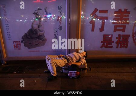 Un passeggero cinese dorme e attende il suo treno presso la piazza della Stazione Ferroviaria di Pechino in Cina, 18 agosto 2018. Passeggeri cinesi sl Foto Stock