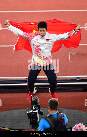 Su Bingtian della Cina pone con la bandiera nazionale cinese per festeggiare dopo la conquista degli uomini 100m finale delle gare di atletica durante il 2018 Asi Foto Stock