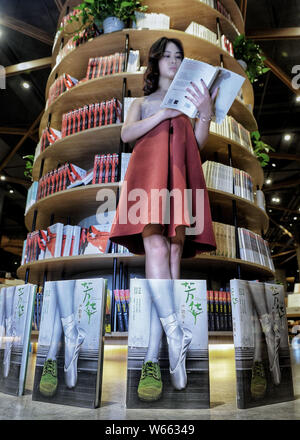 Un membro del personale di Chengdu Yan Ji Bookstore si pone per una prospettiva forzata fotografia con la copertina del libro di "Lei mi ha toccato' da cino-americano w Foto Stock