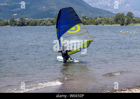 Il lago di Como, Italia - 21 luglio 2019. Sport d'acqua: windsurf arrampicata su una scheda su un luminoso giorno di estate vicino a Colico, città d'Italia. Alp mountai Foto Stock