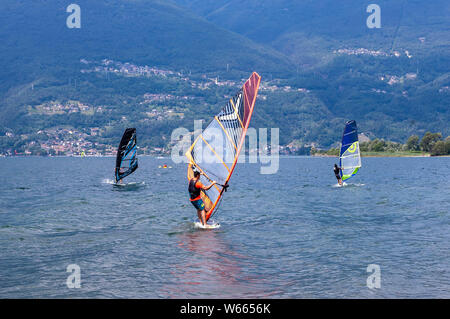 Il lago di Como, Italia - 21 luglio 2019. Sport d'acqua: gruppo di tre windsurf Surf il vento sulle onde su una soleggiata giornata estiva vicino a Colico, città in Ita Foto Stock