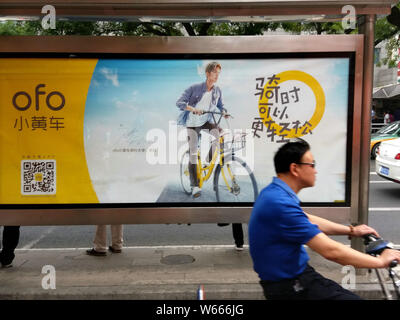 --FILE--un ciclista passa su un annuncio pubblicitario per il cinese bike sharing service ofo su una strada a Pechino, in Cina, il 5 giugno 2017. Cina-basato ofo annou Foto Stock