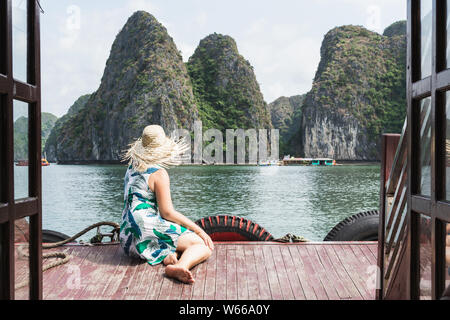 Giovani caucasici donna bionda in un cappello di paglia godendo il giro in barca ai Lan Ha Bay, Cat Ba island, Vietnam Foto Stock