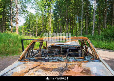 Bruciata auto da dietro al bordo della strada nella foresta Foto Stock