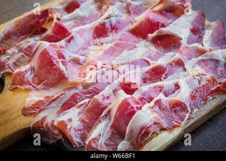 Prosciutto Iberico tagliati su una tavola di legno, spagnolo tapa tipica Foto Stock