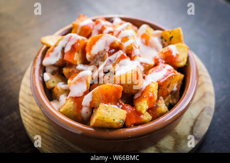 Spagnolo patatas patate bianche per le tapas con pomodoro e salsa piccante su una tazza Foto Stock