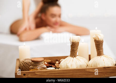 Donna relax nella spa salone con sacchetti a base di erbe sul vassoio in legno Foto Stock