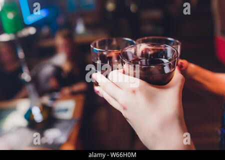 Mani maschio allegria con bicchieri di shot o liquore. Amici bere shot o liquore e cheers. Maschio di allietare le mani con alcool sulla barra sfocata sullo sfondo Foto Stock