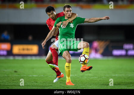 Il croato giocatore di calcio Nikica Jelavic, destro di Guizhou Hengfeng passa la palla contro un giocatore di Guangzhou Evergrande Taobao nel loro dodicesimo round Foto Stock