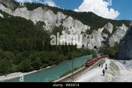 Versam, GR / Svizzera - 30. Luglio 2019: escursionisti e la Ferrovia Retica sulle rive del fiume Reno nella gola di Ruinaulta nelle Alpi Svizzere Foto Stock