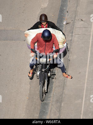 Un due mens cercando trasporta carichi eccessivi, sacchetto di grandi dimensioni su un motociclo, a Saigon, Vietnam. Foto Stock