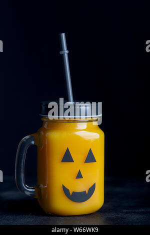Halloween sano di zucca o carota bevande nel vasetto di vetro su uno sfondo nero Foto Stock
