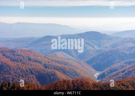 Bella la natura in autunno sfondo. cielo blu con nuvole sopra le montagne. colline boscose in caduta rossastro colore. pomeriggio nebuloso clima Foto Stock