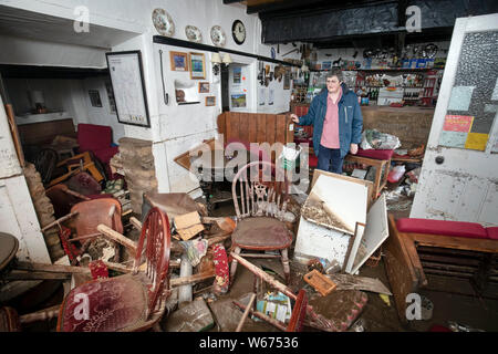 Rowena Hutchinson, proprietario del Red Lion Inn in Langthwaite, North Yorkshire, sorge nella zona bar del suo pub che è stato devastato da acqua di inondazione, dopo le parti della regione avevano fino a 82.2mm di pioggia in 24 ore il martedì. Foto Stock