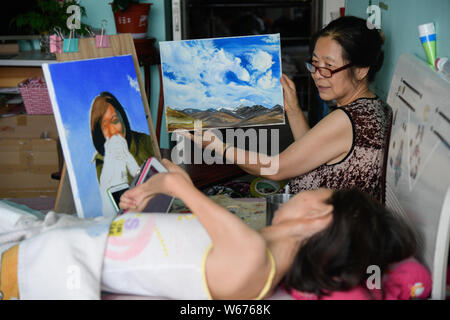 La madre di 40-anno-vecchio donna cinese Zhang Junli, che ha paralizzato da lei era 8, si prepara per la confezione di un dipinto ad olio creato da Zhang Foto Stock