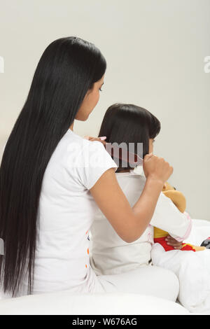 Donna pettinatura di sua figlia di capelli Foto Stock