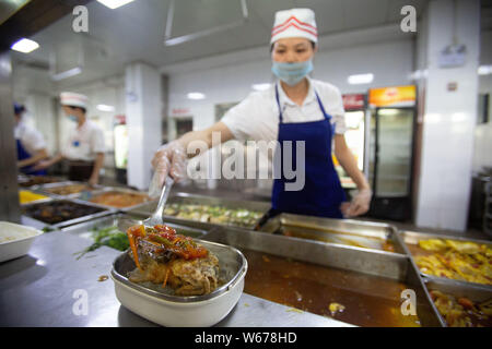 Un personale cinese serve piatti di pesce che vengono raccolte dal lago Xinghu nel campus del Guangxi Medical University, agli studenti gratuitamente presso il Foto Stock