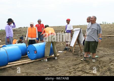 Un gruppo di giovani adulti si riuniscono accanto a una diga d'acqua e discutere circa il loro piano di attività all'aperto su una lavagna bianca. Foto Stock