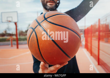 Close up uomo attraente holding basket. La sfera è sul fuoco e primo piano. La formazione outdoor Foto Stock