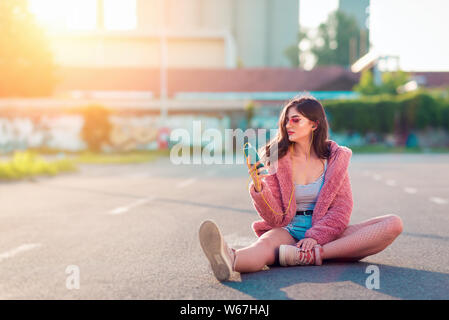 Giovani moda donna ascoltando musica su cuffie e lo smartphone Foto Stock