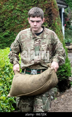 Un soldato da 2 Yorks Stack i sacchi di sabbia in Grinton, North Yorkshire dopo che parti della regione avevano fino a 82.2mm di pioggia in 24 ore il martedì. Foto Stock