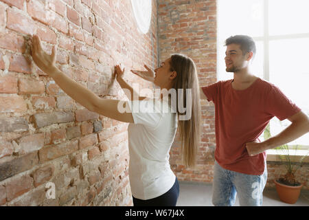 Coppia giovane facendo appartamento riparare insieme se stessi. Uomo sposato e la donna facendo home makeover o rinnovo. Concetto di relazioni, la famiglia, l'amore. La misurazione della lunghezza per il futuro design. Foto Stock