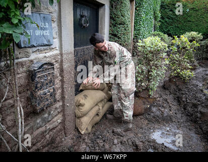 Un soldato da 2 Yorks Stack i sacchi di sabbia in Grinton, North Yorkshire dopo che parti della regione avevano fino a 82.2mm di pioggia in 24 ore il martedì. Foto Stock