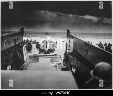 Fotografia di sbarco in Normandia, campo di applicazione e il contenuto: didascalia originale: verso il fondo della rampa di una guardia costiera sbarcano chiatta soldati Yankee tempesta verso la spiaggia di fuoco di spazzamento di Nazi difensori del D-Day invasione della costa francese. Truppe davanti può essere visto che giace piatto sotto la micidiale mitragliatrice la resistenza dei tedeschi. Presto i Nazisti furono condotti posteriore sotto la schiacciante forza di invasione gettati in dalla Guardia Costiera e Marina artigianato anfibio. Note generali: questo è il titolo ufficiale assegnato dalla guardia costiera. Foto Stock