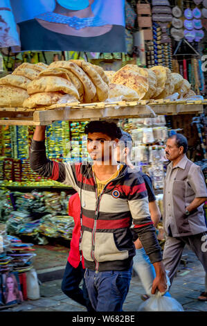 Un giovane uomo trasporta il pane nelle strade del Bazaar di Khan El Khalili al Cairo Foto Stock