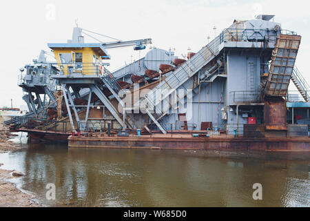 Draga per assorbimento di bunker del rimorchio durante il lavoro sulla bonifica del terreno per nuove porte. Draga aspirante. Il dragaggio in fairway di fiume. Aspirazione di taglio Foto Stock