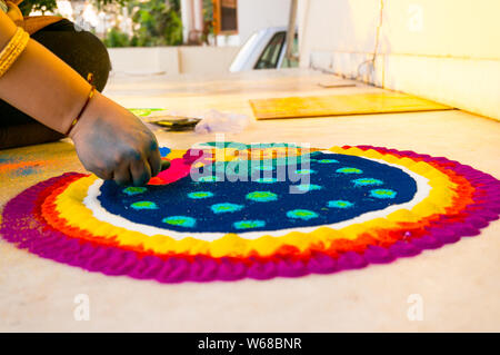 La mano del giovane ragazza indiana rendendo rangoli dalla polvere colorata il Diwali eve. Questi bellissimi disegni sono realizzati in ogni casa indù per decorare e celeb Foto Stock